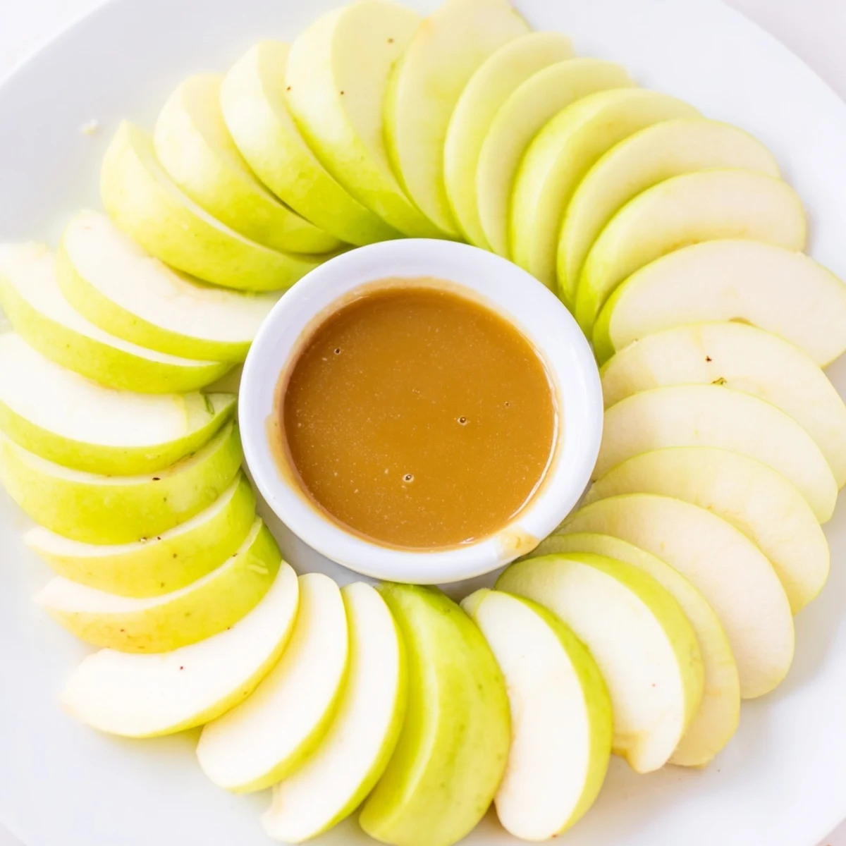 Fresh apple slices with caramel dip, perfect appetizer for sharing.