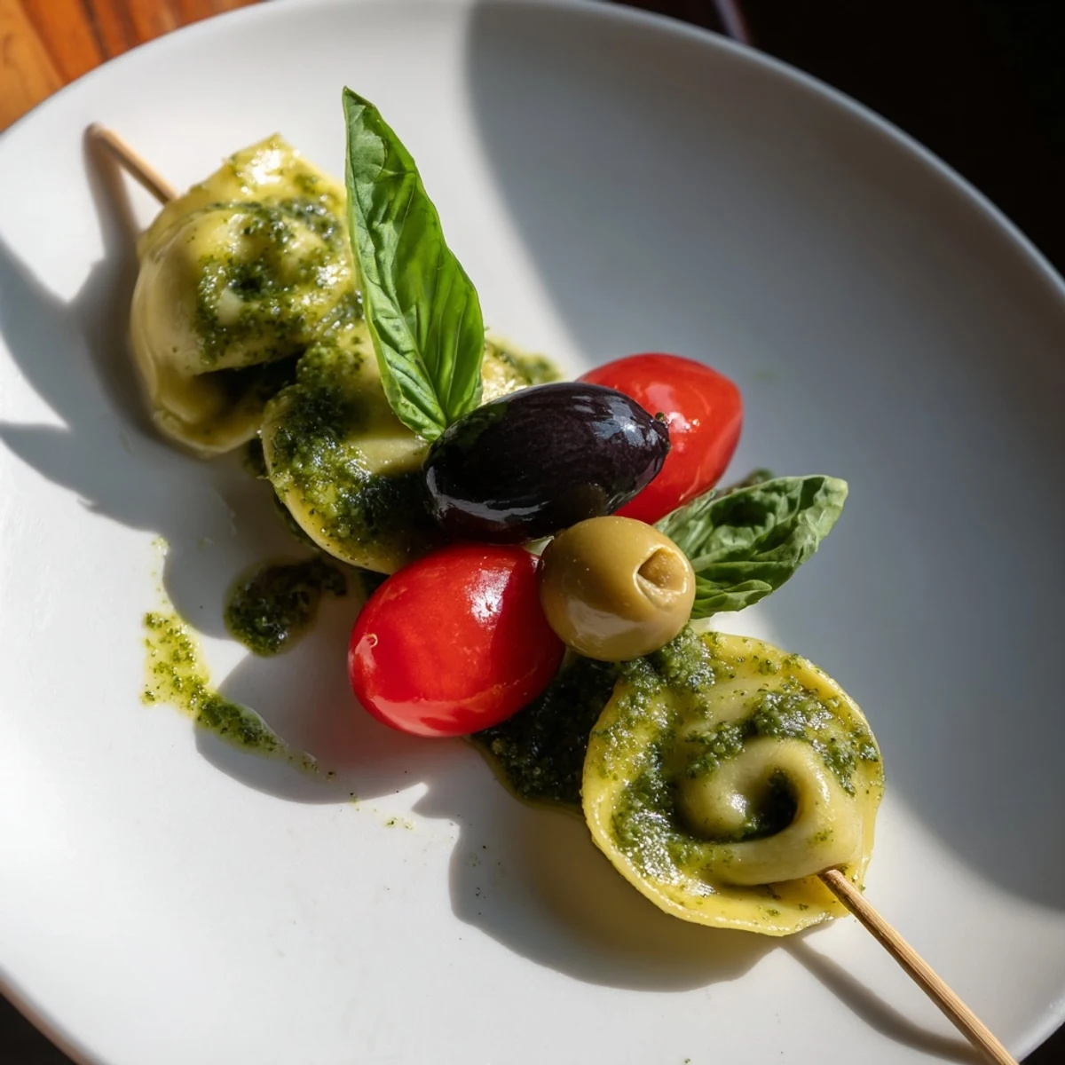Appetizer Skewers: colorful tortellini, juicy cherry tomatoes, and olives drizzled with pesto, ready to serve.