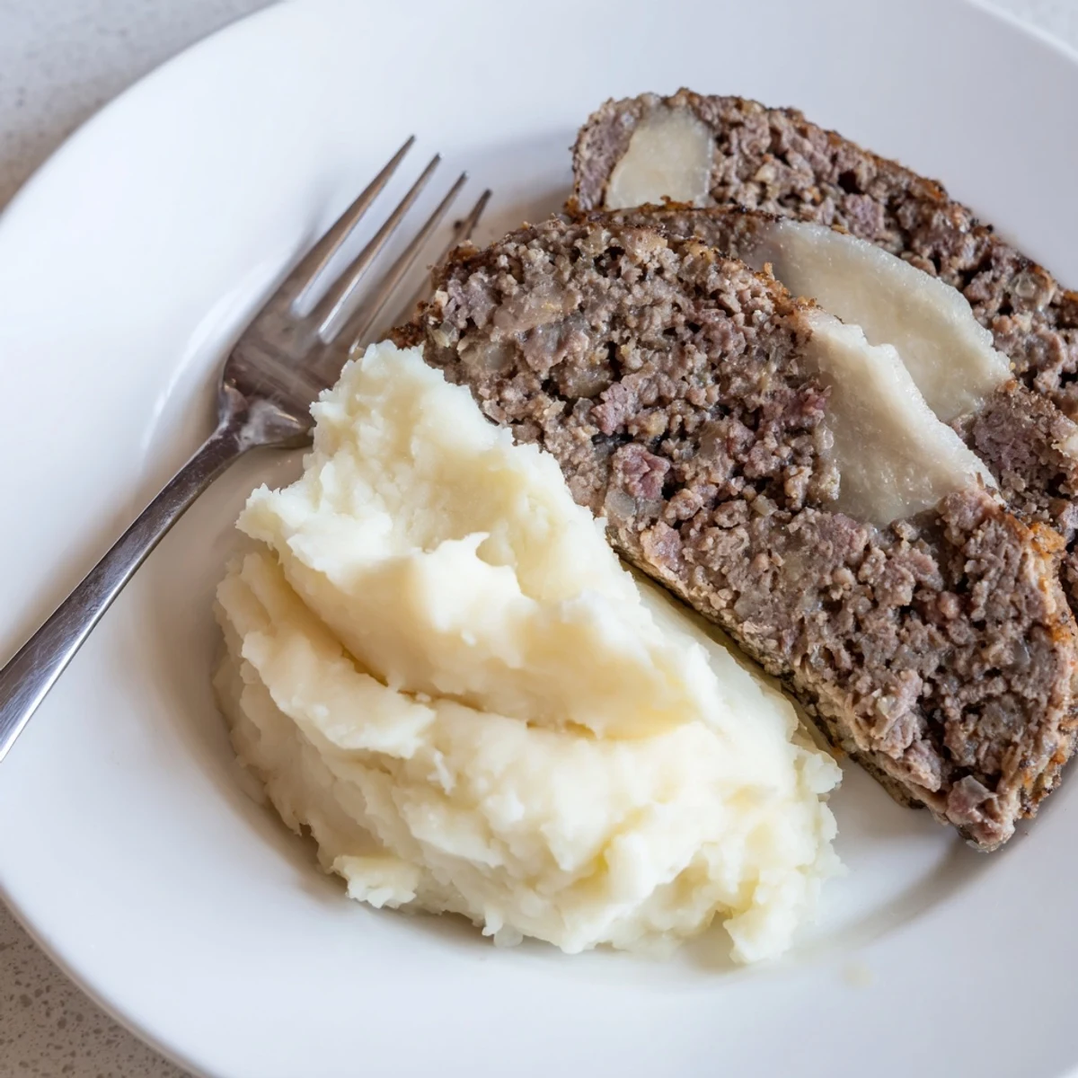 A plate of steaming Scottish haggis, savory and textured, served alongside mashed potatoes and turnips.