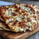 Warm The Best Easy Garlic Naan Bread stacked on a plate, ready to scoop up creamy curry or enjoy plain.