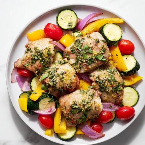 Tender basil-infused chicken breasts nestled amongst colorful roasted veggies for this delicious sheet pan dinner.