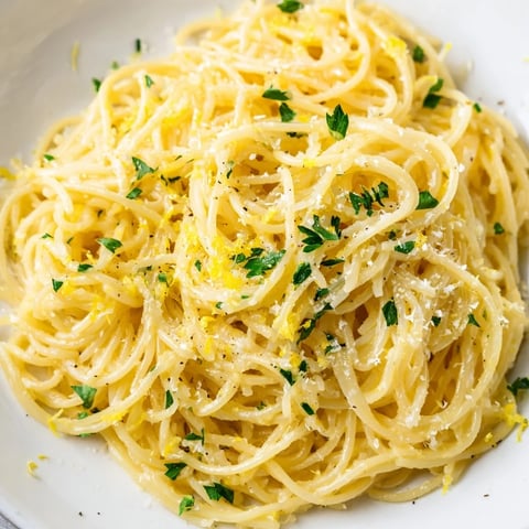 A close-up of Lemon Butter Pasta Light, featuring silky capellini tossed in a glossy lemon-butter sauce with fresh parsley and grated Parmesan.
