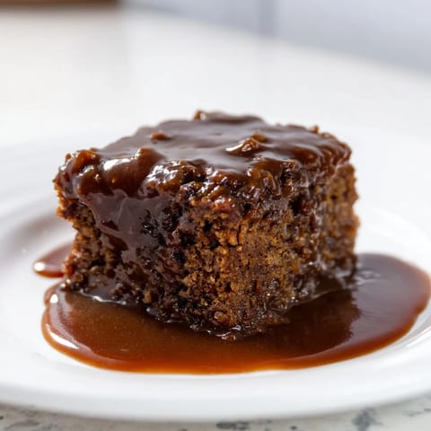 Close-up of baked Weekend Cabin Style Sticky Toffee Pudding, a rich dessert, ready to serve with sauce.
