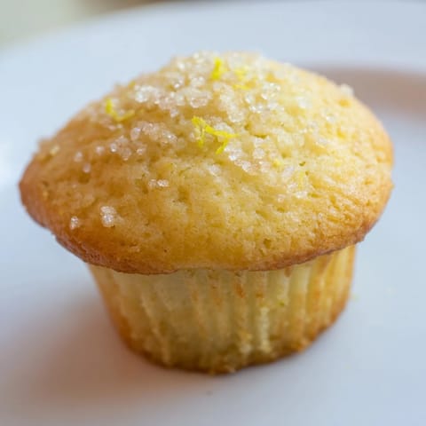 Close-up of freshly baked Simple Sweet Lemon Zest Muffins, smelling of bright lemon and vanilla.