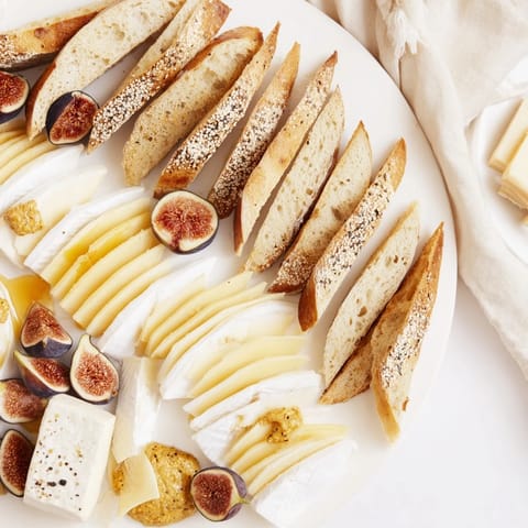 Taste the delightful French Bistro Elegance: creamy cheeses, fresh baguette, and sweet grapes on display.