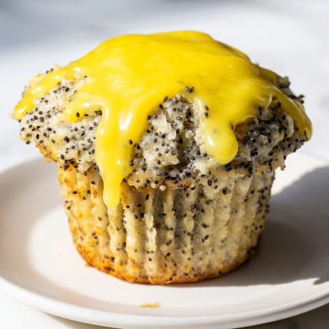A close-up of freshly baked lemon poppy seed muffins, showing texture and poppy seed specks.