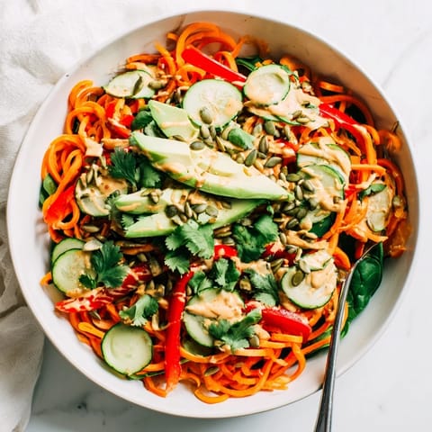 Vibrant spiralized carrot noodles in a Skincare Bowl with cucumber, red pepper, and fresh cilantro.
