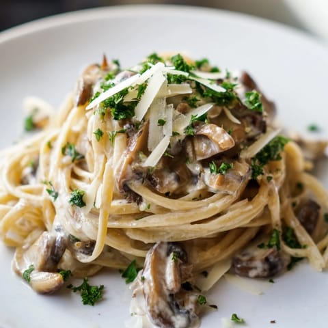 A close-up of Creamy Mushroom Linguine highlights al dente pasta strands coated in luscious sauce, with shaved Parmesan and a glass of Chardonnay nearby.  