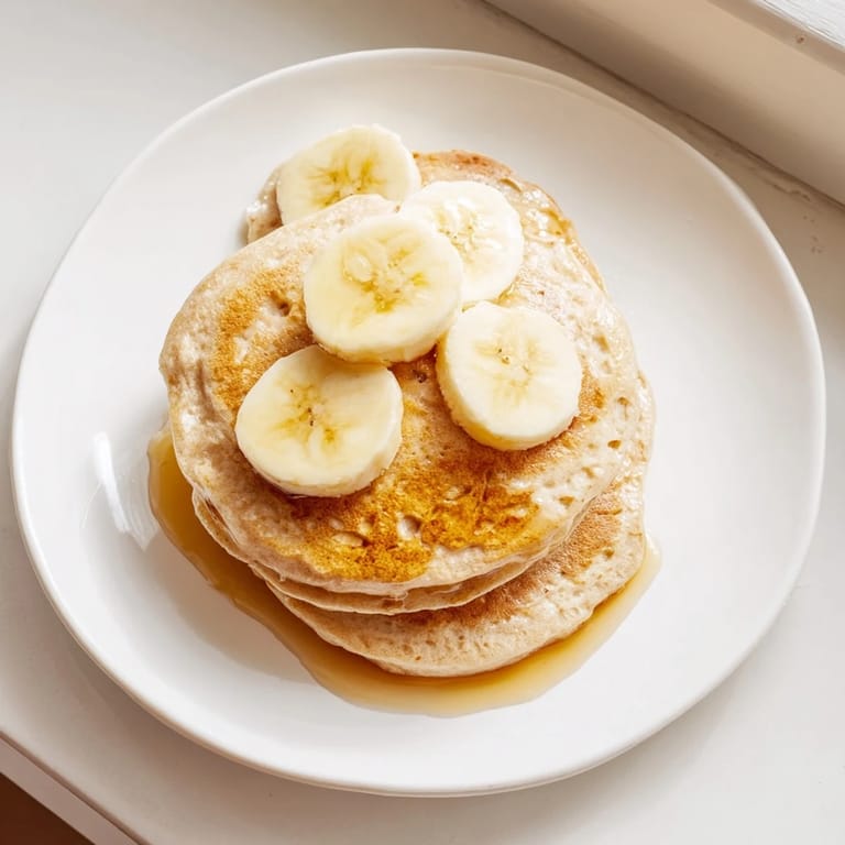A plate of fresh, homemade Golden-Brunch Banana Pancakes with a sweet maple drizzle, ready to enjoy.