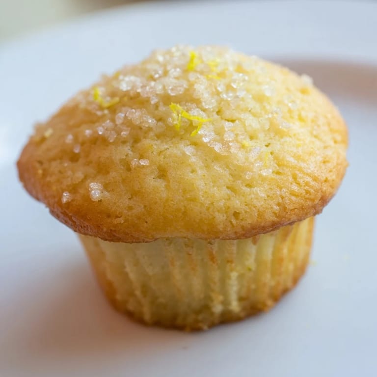 Close-up of freshly baked Simple Sweet Lemon Zest Muffins, smelling of bright lemon and vanilla.