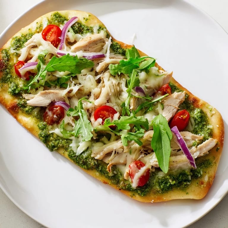 Delicious Italian-inspired Pesto Chicken Flatbread, a quick weeknight meal with flavorful pesto and toppings.