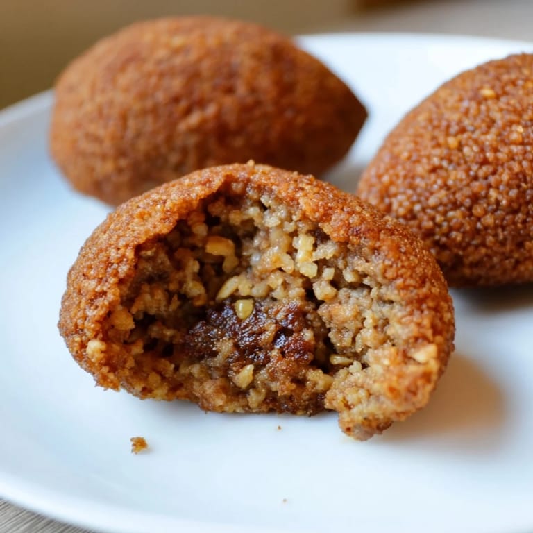 A plate of fried Lebanese Kibbeh, showing the savory spiced meat and bulgur dough exterior.