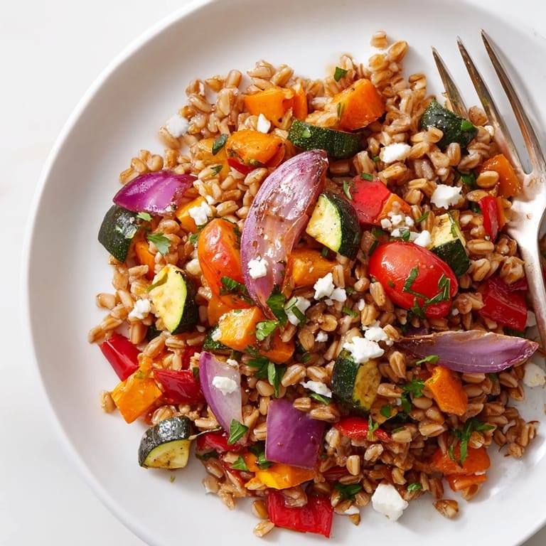 Freshly prepared farro with roasted vegetables drizzled with extra-virgin olive oil and garnished with parsley, perfect for a vegan main dish.