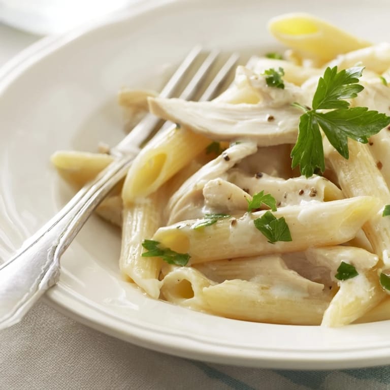 Hearty roasted garlic chicken penne twirled on a fork, steam rising from silky Parmesan cream sauce.