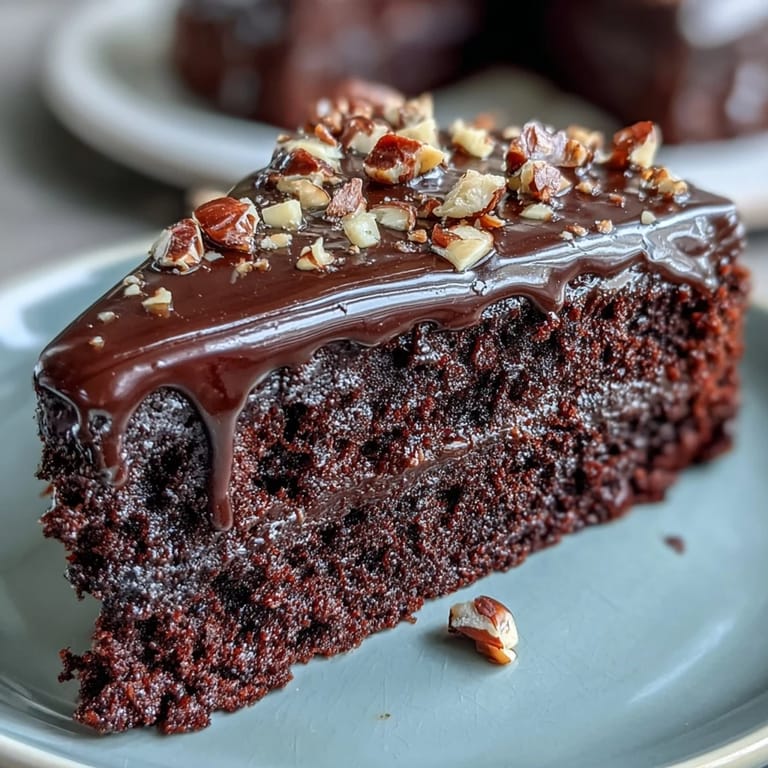 A plated slice of Chocolate Celebration Cake reveals tender crumb, dark chocolate ganache, and sparkling hazelnut praline shards. 
