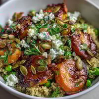 Warm quinoa bowl with roasted carrots and green peas, topped with fresh parsley and a zesty lemon dressing.  