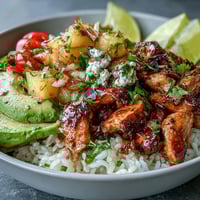 Vibrant chicken pineapple taco bowls with coconut rice, topped with fresh pineapple salsa and avocado slices for a tropical twist.