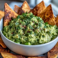 Creamy edamame guacamole served with golden, crisp pita chips for a healthy, protein-packed snack.  