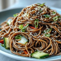 Cold soba noodle salad glistening with vibrant sesame ginger dressing.